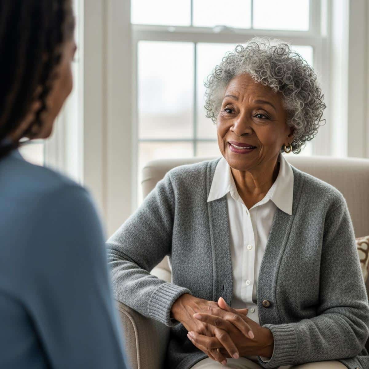 Older woman with gray hair listening thoughtfully to granddaughter, centered waist-up view